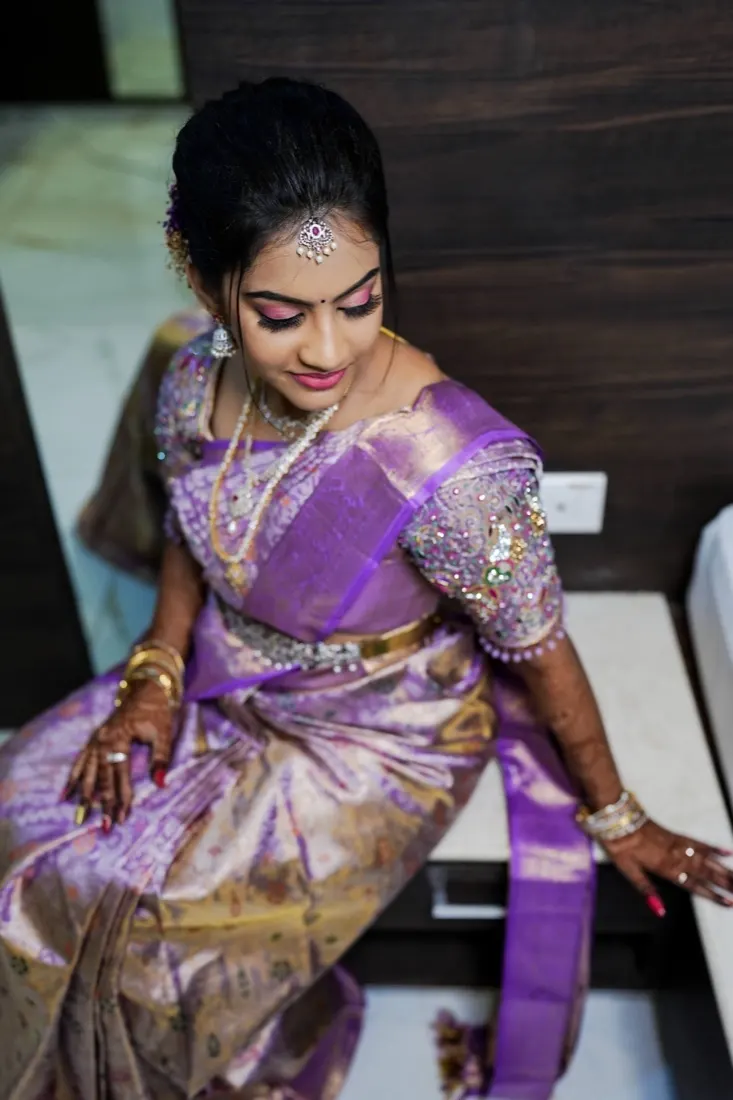 Bride seated in a lavender and gold pattu saree