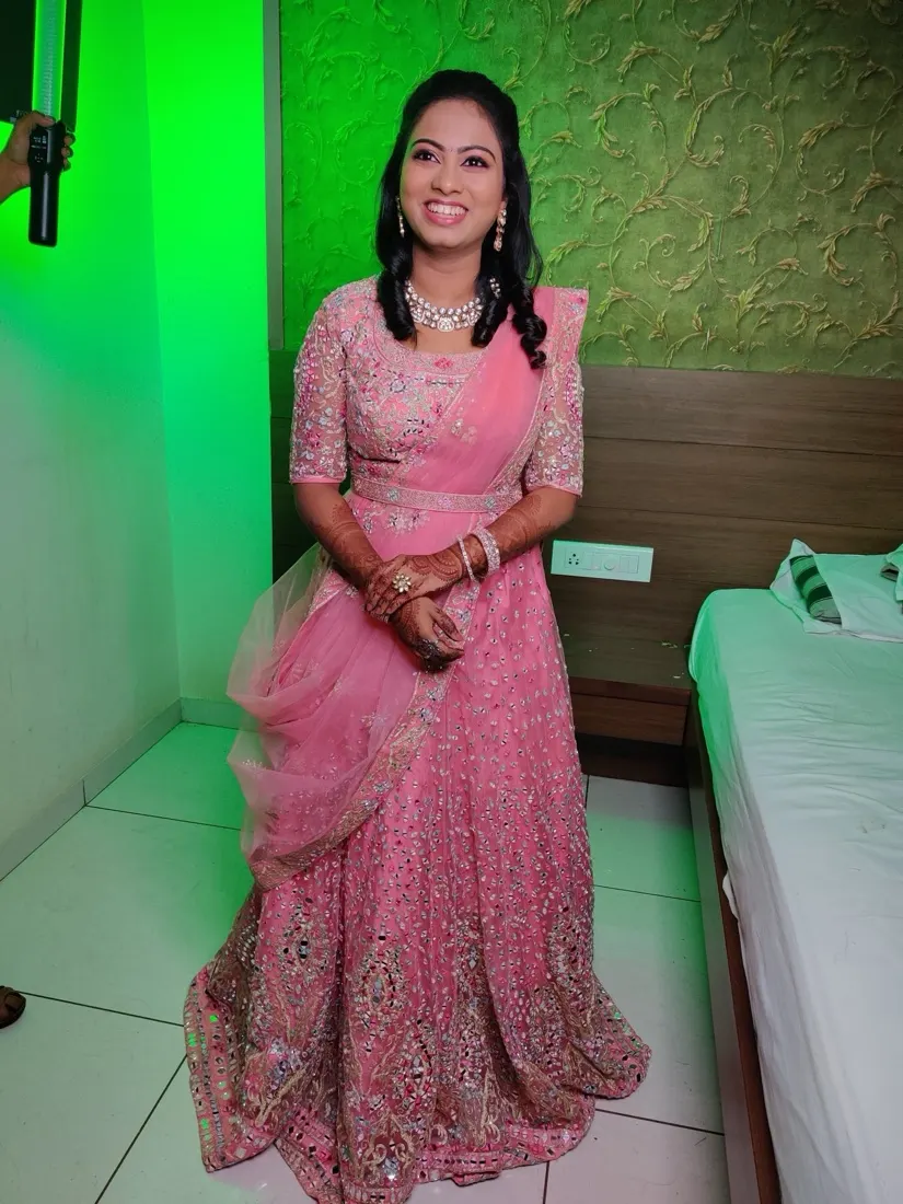 Bride in an embroidered blush lehenga with soft open curls