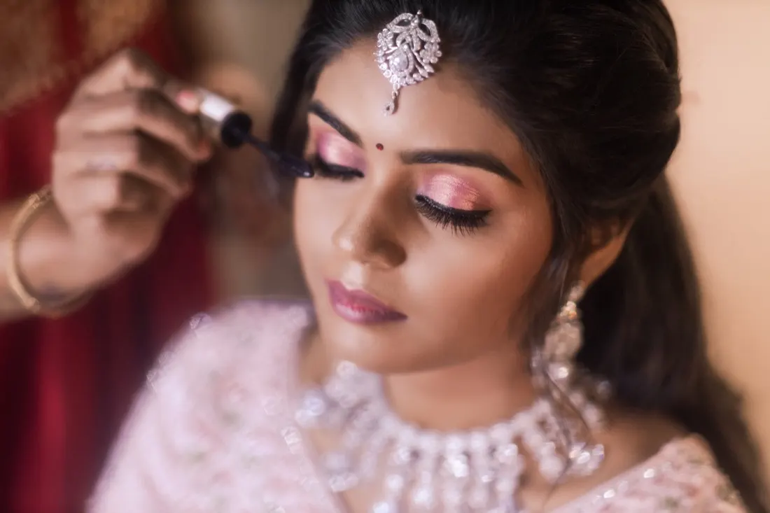 Mascara going on a bride's lashes, eyes lowered, pink lids