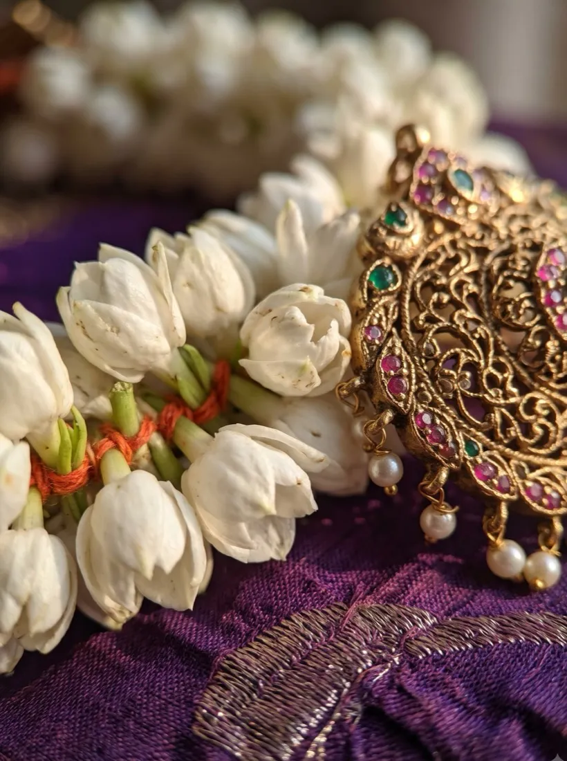 Fresh jasmine strands wound with a gold jadai billai on purple silk