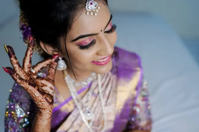Mehendi hands raised to a bride’s cheek